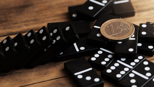 Shiny one euro coin lying on top of spilled domino tiles.