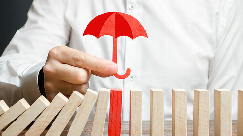 A businessman insures red dominoes and stops the collapse of the whole system. Insurance and risk management. Accurate forecasts and miscalculations. Financial support, subsidies and exemptions