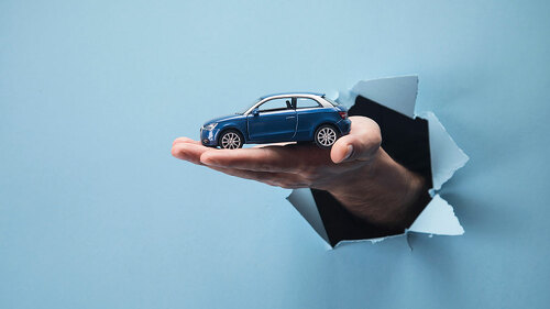 Man's hand holding a car on a blue background