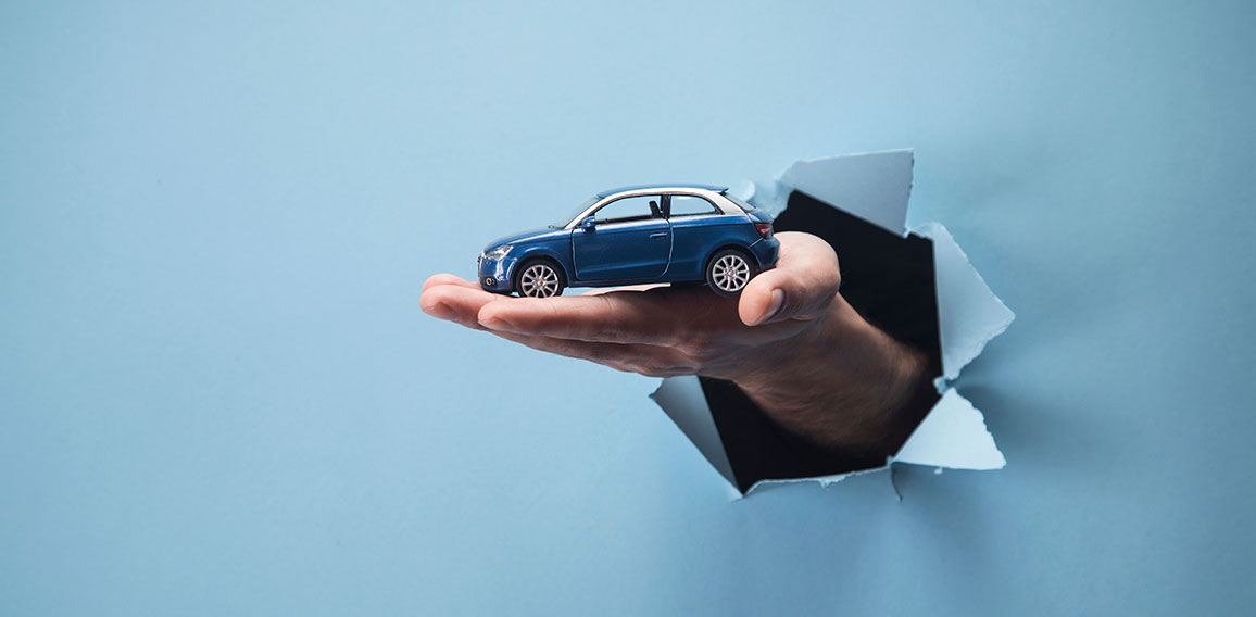 Man's hand holding a car on a blue background