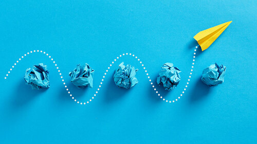 Paper plane passes through the crumpled paper balls.