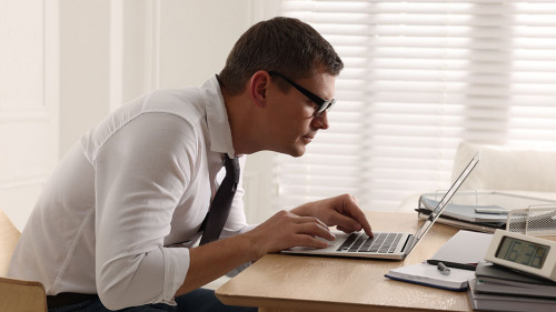 Man with bad posture working on laptop in office