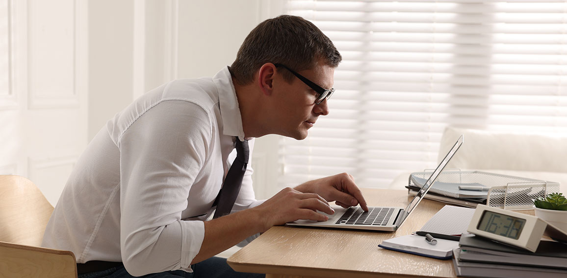 Man with bad posture working on laptop in office