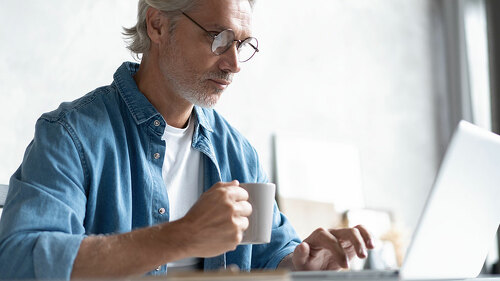 Middle-aged man working from home-office on laptop.