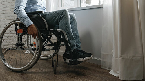 Disabled man sitting in a wheelchair and wearing face mask