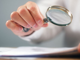 Businessman with magnifying glass reading documents