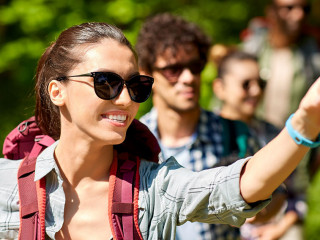 group of friends with backpacks hiking in forest