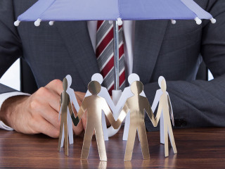 Businessman Sheltering Paper People With Umbrella