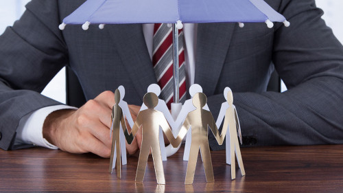 Businessman Sheltering Paper People With Umbrella