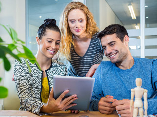 Smiling business team working together with tablet in the office