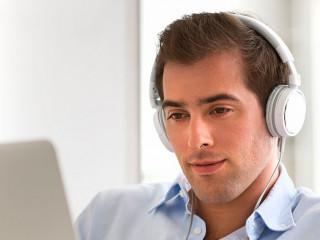 Portrait of  young handsome guy with laptop using headset