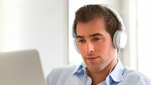 Portrait of young handsome guy with laptop using headset