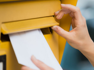 Woman's Hands Inserting Letter In Mailbox