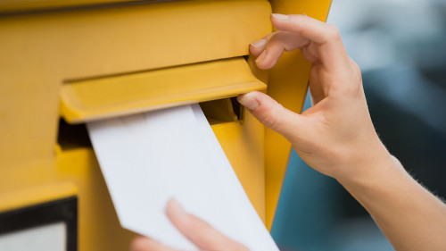 Woman's Hands Inserting Letter In Mailbox