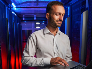 Bearded confident maintenance engineer in white shirt is working in database center