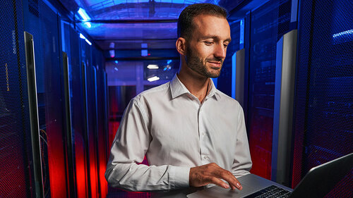 Bearded confident maintenance engineer in white shirt is working in database center