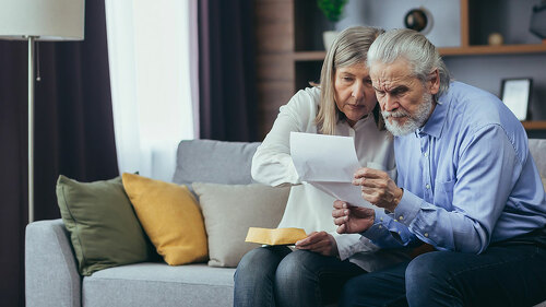Angry frustrated document senior couple. Unhappy old family getting stressed. Serious older husband showing banking paper document bills taxes to confused elderly wife in home. Worried looking utility