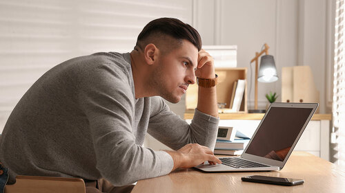 Man with poor posture using laptop at table indoors