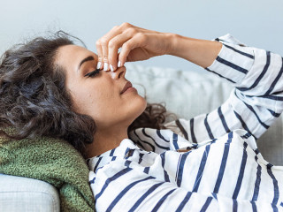 Upset depressed young woman lying on couch feeling strong headac