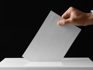 Man putting his vote into ballot box on black background, closeu