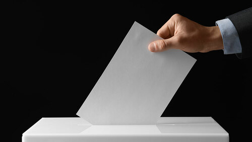 Man putting his vote into ballot box on black background, closeu