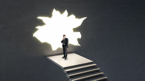 Thoughtful businessman on stairs looking out of hole in broken wall into a bright future. Market research, success, tomorrow and crisis ideas concept.