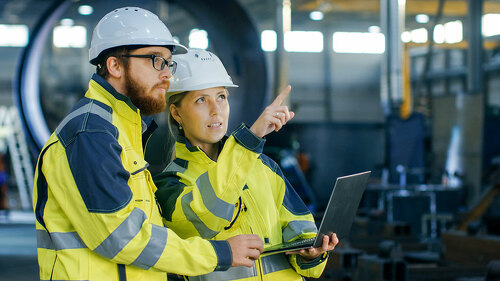 Portrait of Male and Female Industrial Engineers in Hard Hats Di