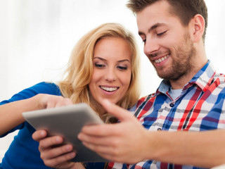 Smiling couple using digital tablet at home