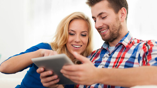Smiling couple using digital tablet at home