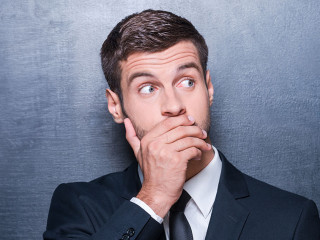 No way! Shocked young man in formalwear covering mouth with hand