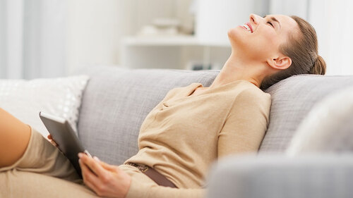 Relaxed young woman sitting on sofa with tablet pc