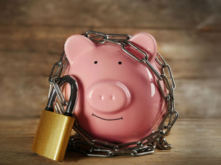 Piggy bank and chains on wooden background