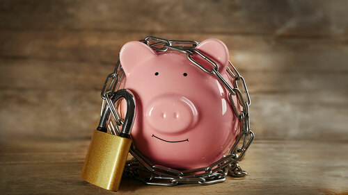 Piggy bank and chains on wooden background