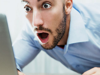 uomo stupito davanti al monitor del notebook