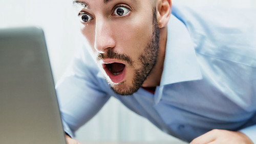 uomo stupito davanti al monitor del notebook