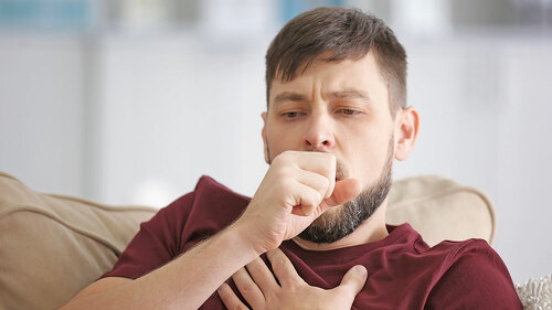 Young ill man sitting on sofa at home