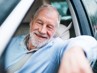 Happy senior man sitting in car in driver seat.