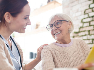 Red-haired nurse smiling while talking to kind aged woman