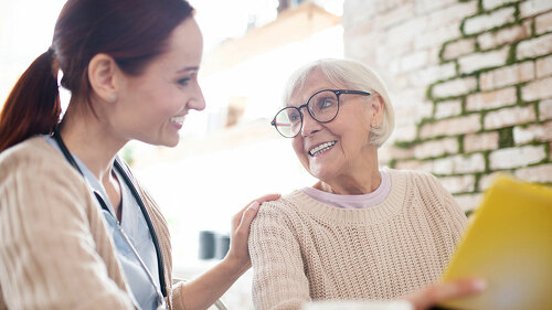 Red-haired nurse smiling while talking to kind aged woman