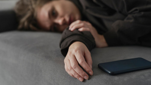 Caucasian woman with mental problem lying down with mobile phone on couch