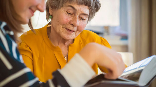Old woman with her granddaughter look at family photos.