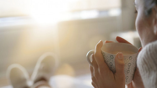 Cosy brunette at home on couch with hot drink