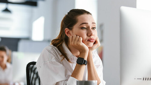 Bored young woman dressed in shirt sitting at her workplace