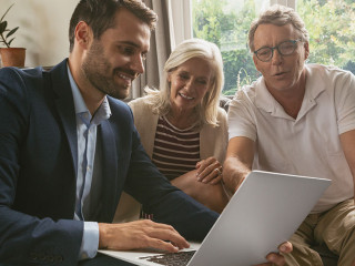 Active senior couple discussing with real estate agent over lapt