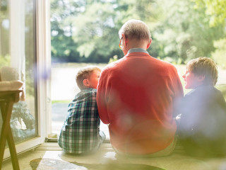 Grandfather and grandsons sitting in doorway
