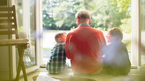 Grandfather and grandsons sitting in doorway