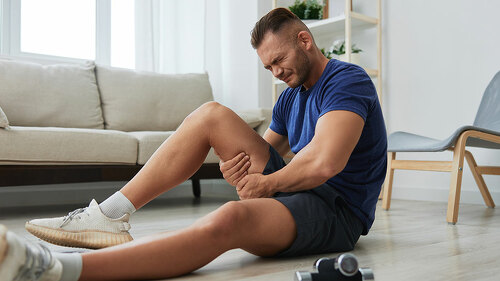 Man athlete pain and injury back arm and leg at home, sports injury bodybuilder, concept health and beauty