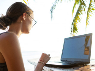 freelancer girl with a computer among tropical palm trees work o