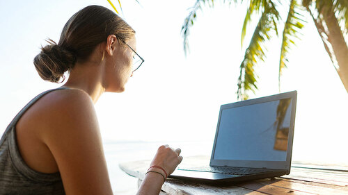 freelancer girl with a computer among tropical palm trees work o