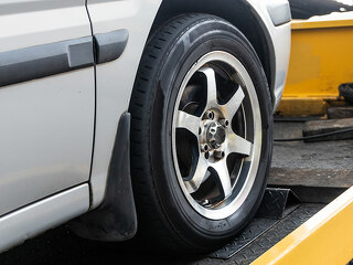 Broken down car towed onto flatbed tow truck with hook cable